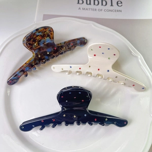 Three premium acetate shark hair clips with colorful rhinestones on a ceramic tray