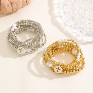 Dettaglio dei bracciali elastici con perline oro e argento e ciondoli a forma di croce