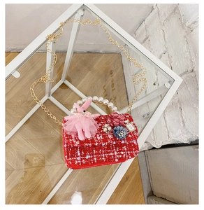 Detail of red tweed girls mini bag with pearl handle and pink bunny pendant charm