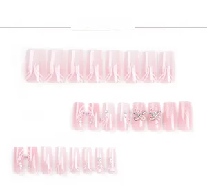 Detailed flat lay of pink press-on nails with 3D flowers, pearls and silver bow charms