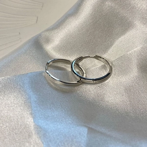 Orecchini a cerchio minimalisti in argento sterling S925 su sfondo di seta bianca