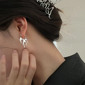 Detail of silver liquid metal flame earring and matching hair claw clip on model