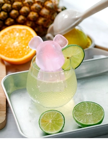 Detalle de un cubito de hielo rosa con forma de oso en una bebida fría con cítricos