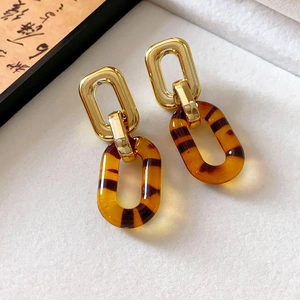 Close-up of golden metal links and translucent tortoiseshell resin drop earrings