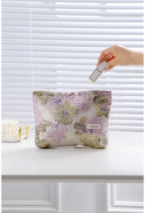 Détail de la trousse de maquillage en jacquard floral rose et doré au style vintage
