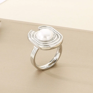 Macro shot of silver geometric ring featuring a pearl inlay on a textured metal band