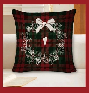 Detail of red and green plaid pillowcase with white Christmas wreath on a soft sofa