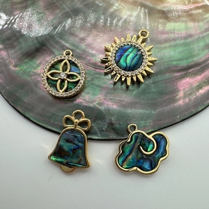 Macro shot of 18K gold plated shell pendants including star and bell charms for DIY jewelry