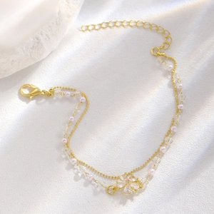 Dettaglio del bracciale a doppio strato dorato con perline e ciondolo a fiore di diamante
