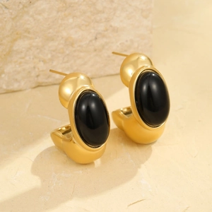 French vintage style C-shape gold earrings with oval black stones on stone background