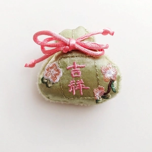 Detailed view of 5x5.5cm green silk pouch brooch with pink floral embroidery and tie