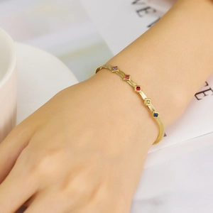 Close-up of golden snake chain bracelet with five colorful square zircon stones on wrist