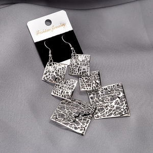 Macro detail of silver layered hollow geometric square drop earrings on display card