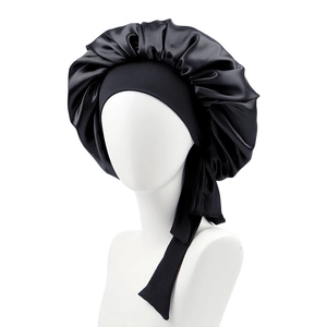 Detail of black satin sleep cap with long adjustable straps and shiny silk texture