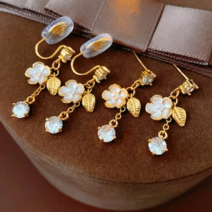 Detailed view of floral tassel earrings with gold plating and clear teardrop gems