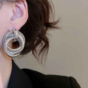 Macro detail of silver irregular multilayer metal earrings with matte and glossy finish