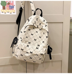 Detail of off-white corduroy backpack with bow embroidery and black ribbon ties