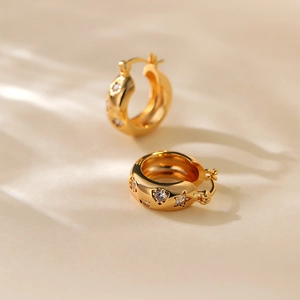 Detailed close-up of gold star-shaped huggie earrings with sparkling zircon stones