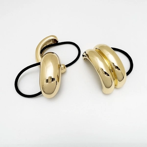 Detail of gold U-shaped alloy hair ties with polished metallic finish and black elastics
