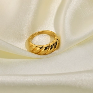 Detailed view of an 18K gold plated croissant ring on a white soft silk fabric