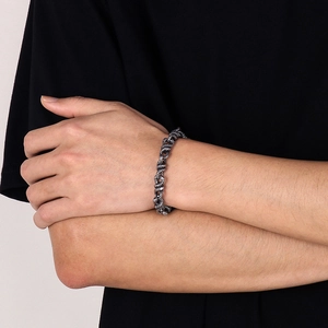 Dettaglio del bracciale a catena serpente in acciaio punk con trama a scaglie al polso maschile