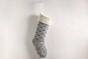 Detail of grey knitted Christmas stocking with white cuff and wavy fish scale texture