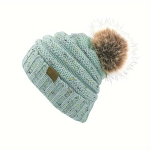 Bonnet d'hiver en maille bleu clair à pois colorés avec un grand pompon en fausse fourrure