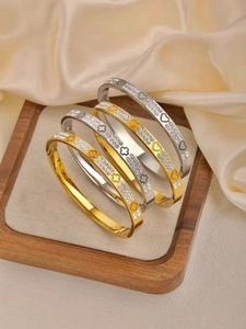 Close-up of gold and silver titanium steel bracelets with crystals on champagne silk