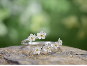 Macro shot of silver daisy ring with gold centers on dark stone, rural style detail