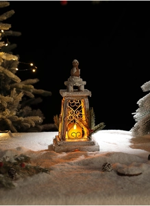 Detail of wooden Christmas lantern with LED candle, fake snow, and pine cone decor