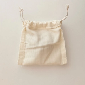 Detailed view of cream corduroy drawstring storage bag with soft vertical texture