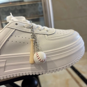 Detail of white platform sneaker featuring a miniature wooden bat and baseball keychain