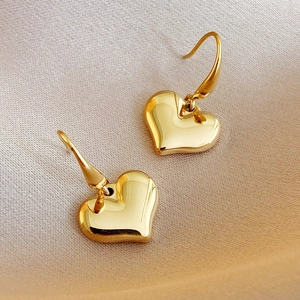 Elegant 14k gold heart-shaped drop earrings displayed on premium champagne silk fabric