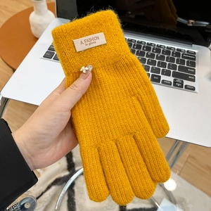 Detail of yellow knit touchscreen gloves featuring white flower decor and ribbed cuff