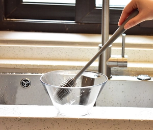 Spazzola in silicone con manico lungo che pulisce una ciotola di vetro in cucina