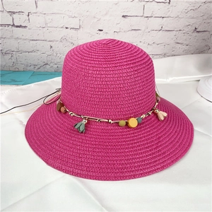 Close-up of pink woven straw sun hat with decorative colorful beads and tassel details