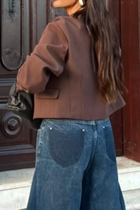 Rear view of a woman wearing a casual brown cropped vest jacket and wide-leg blue jeans