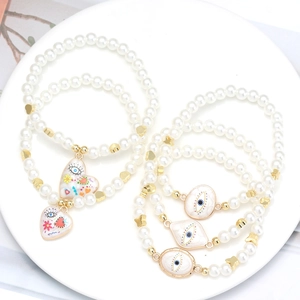 Macro detail of faux pearl bracelets with evil eye charms and golden heart accents