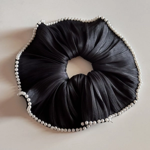 Detail of elegant black pleated satin scrunchie featuring white faux pearl edge trim
