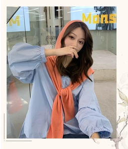 Detail of light blue puff sleeve shirt styled with an orange knitted hooded shawl wrap