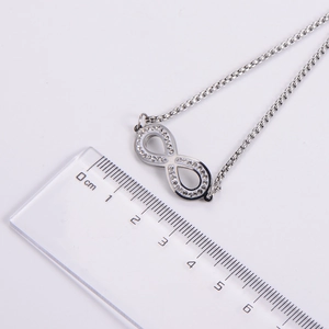 Vue macro du pendentif infini argenté avec strass à côté d'une règle de mesure précise