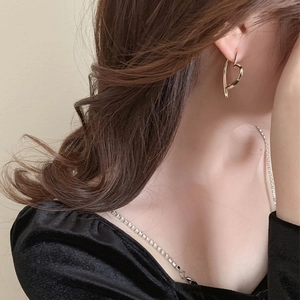 Nahaufnahme eines Models mit polierten goldfarbenen Herz-Ohrringen in glänzendem Metalldesign