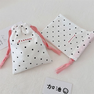 Detail of polka dot drawstring storage bags made of white cotton linen and pink rope