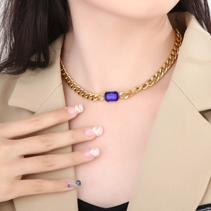 Detail van een gouden Cubaanse schakelketting met vierkante blauwe kristallen hanger