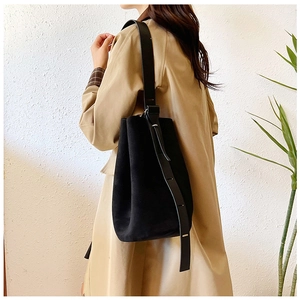 Detail of adjustable leather strap and black suede texture on minimalist bucket bag