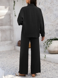 Back view of a black relaxed two-piece set with pleated fabric texture in outdoor setting