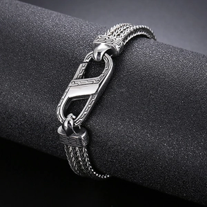 Macro shot of silver woven stainless steel bracelet featuring Greek key pattern clasp