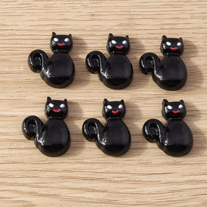 Close-up of six cute black resin cat charms for DIY Halloween crafts on wood background