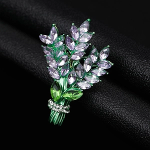 Elegant crystal wheat ear brooch with green and purple stones on black leather background