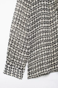 Detailed close-up of geometric print on semi-transparent chiffon shirt with stitching